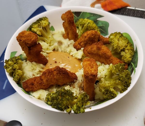 a place with mashed potatoes, brocolli, and dino nuggets